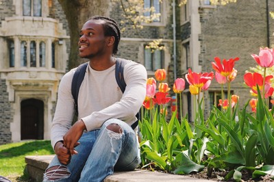 A photograph of Jonathan Rose sitting in the Victoria College quad, in the spring time