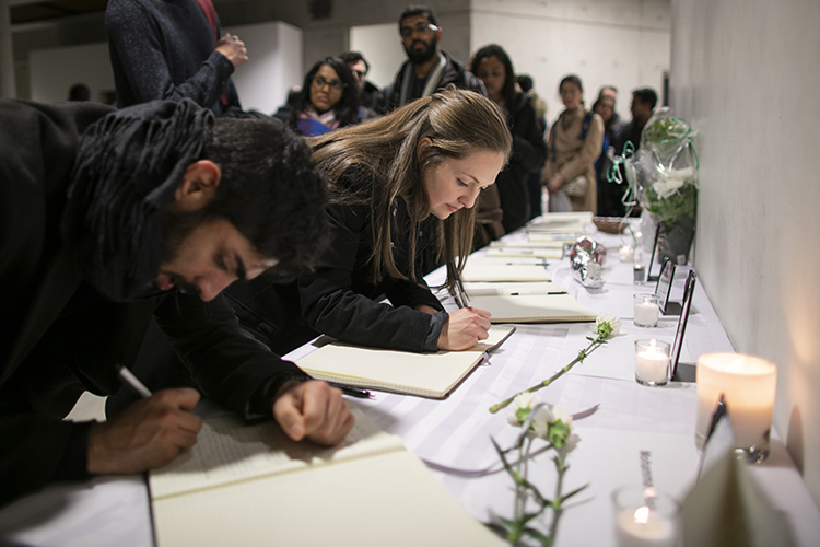 Multiple people line up to sign memorial books.