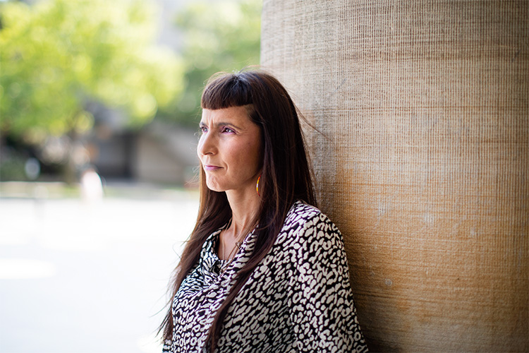 Suzanne Stewart standing against a stone column