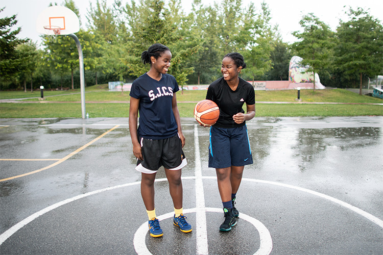 Nakeisha and Mikhaela laughing together on an outdoor basketball court