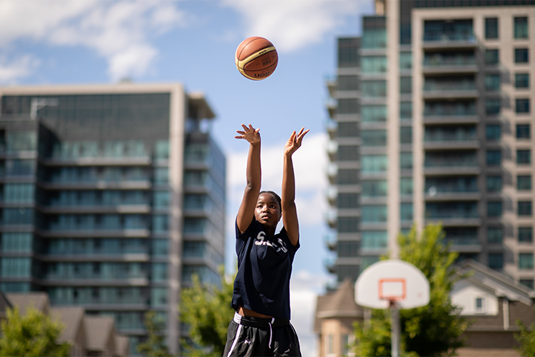Nakeisha Ekwandja shooting a basketball on an outdoor basketball court