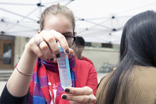A young girl looking at liquid in a syringe