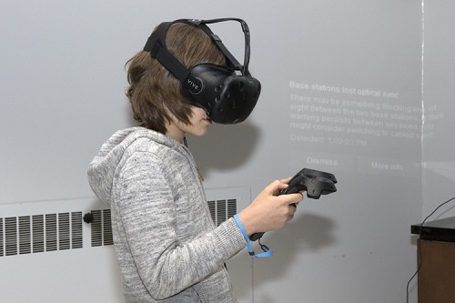 A young boy wearing a VR device on his head with a controller in his hand