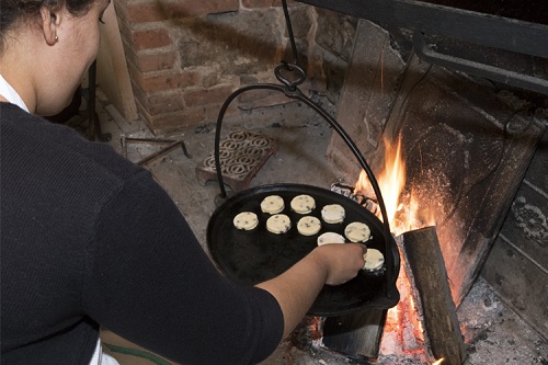 A student cooking cakes over an open fire