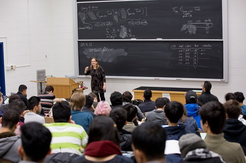 Diane Horton standing in front of a chalkboard teaching computer science students in a lecture hall.