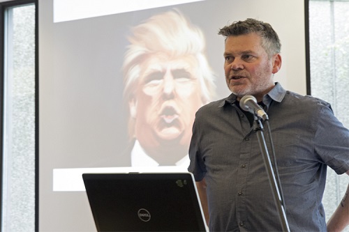 Mark Kingwell presenting in front of a screen with Donald Trump on it