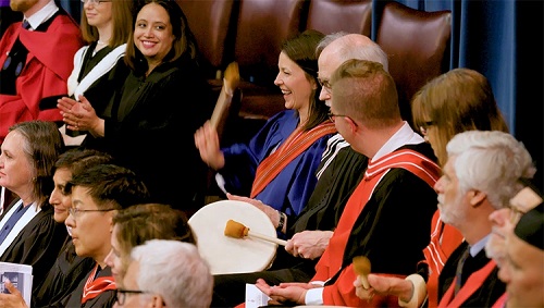 Amanda Carling and Kerry Wilkins play a drum during the convocation ceremony.