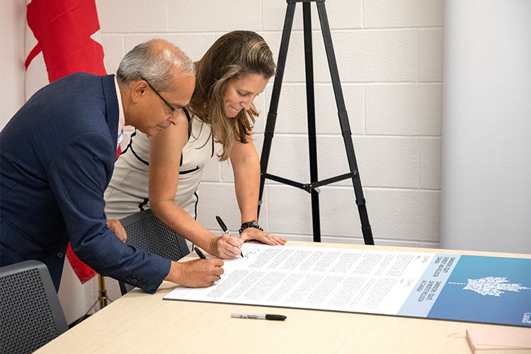 Goel and Freeland signing the Dimensions Charter
