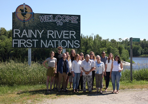 Klassen and team pose in front of Rainy River First Nations welcome sign.