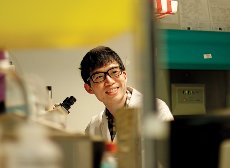 male student wearing lab coat in a research lab