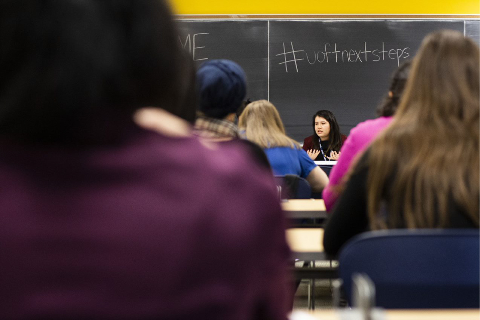 A person at the front of a class answering a question.