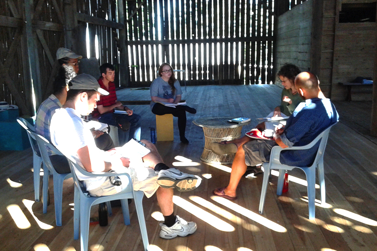 Students sitting on chairs in a circle inside a barn