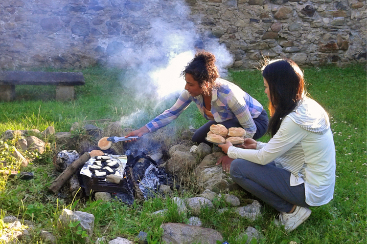 Students cook food on a campfire