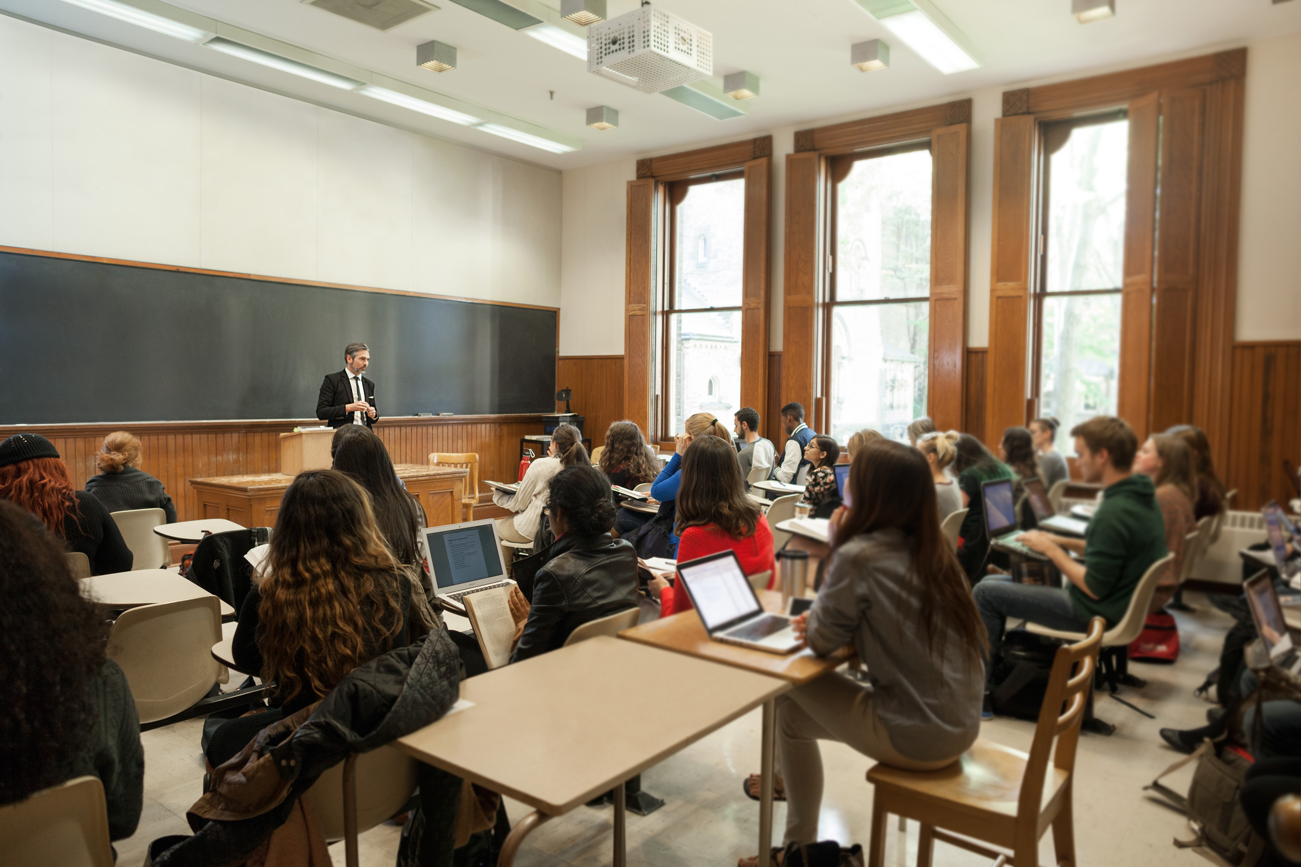 Students in a classroom taking notes as a professor give a lecture