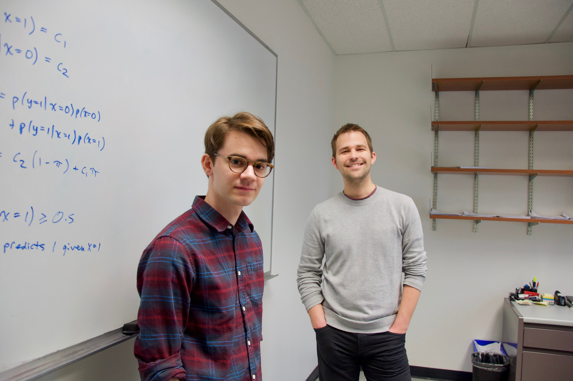 Professor and student in a classroom standing in front of a board with mathematical equations