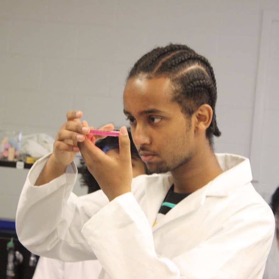 Ashenafee Mandefro, St. Michael's Life Science FLC Peer Mentor in a lab holding a sample