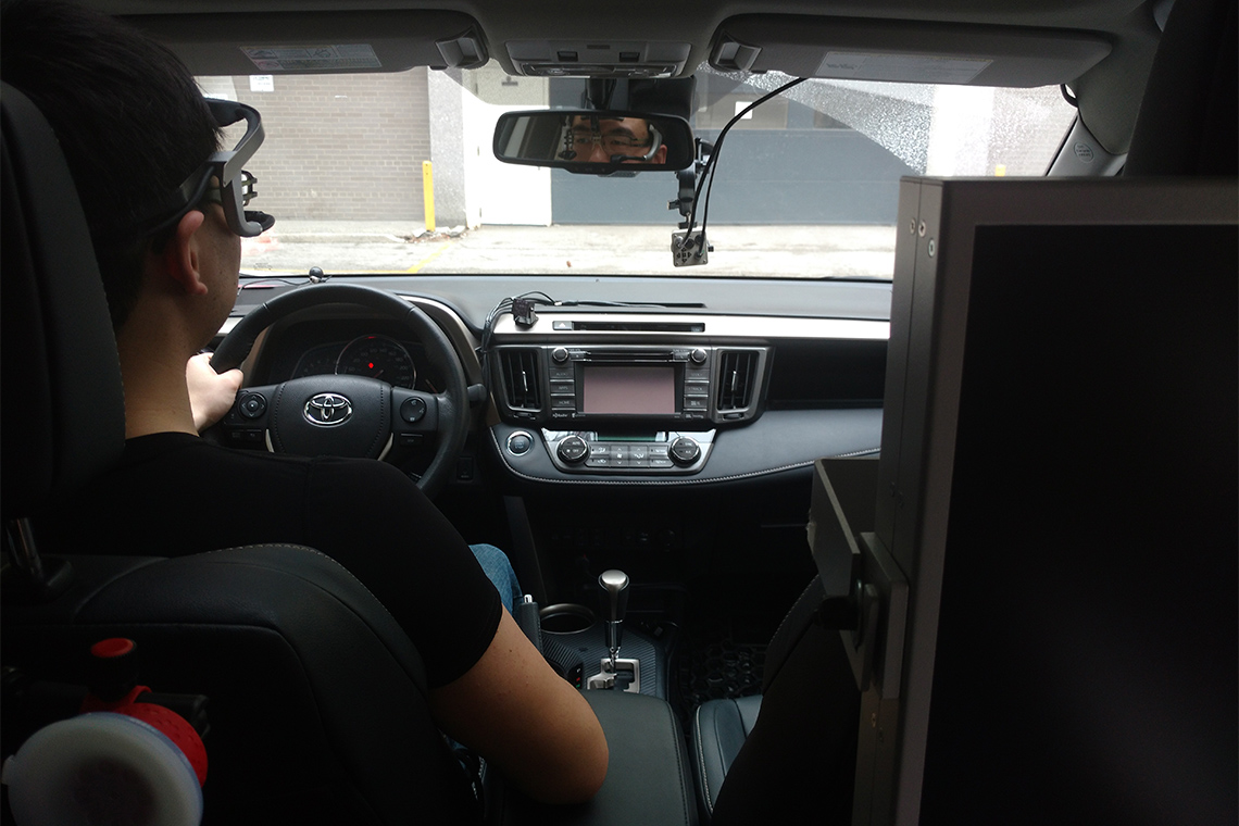 Study participant wearing eye-tracking equipment in the front seat of a vehicle.