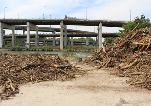 Two piles of wood and trash along a river, under four bridges.