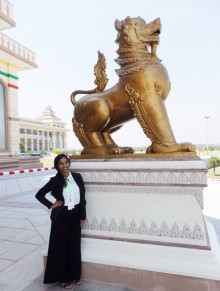 Naveeda Hussain in front of a large gold lion like statue in Burma. 
