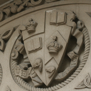 U of T coat of arms in stone on a building.