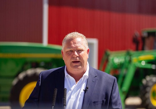 Doug Ford standing in front of tractors.