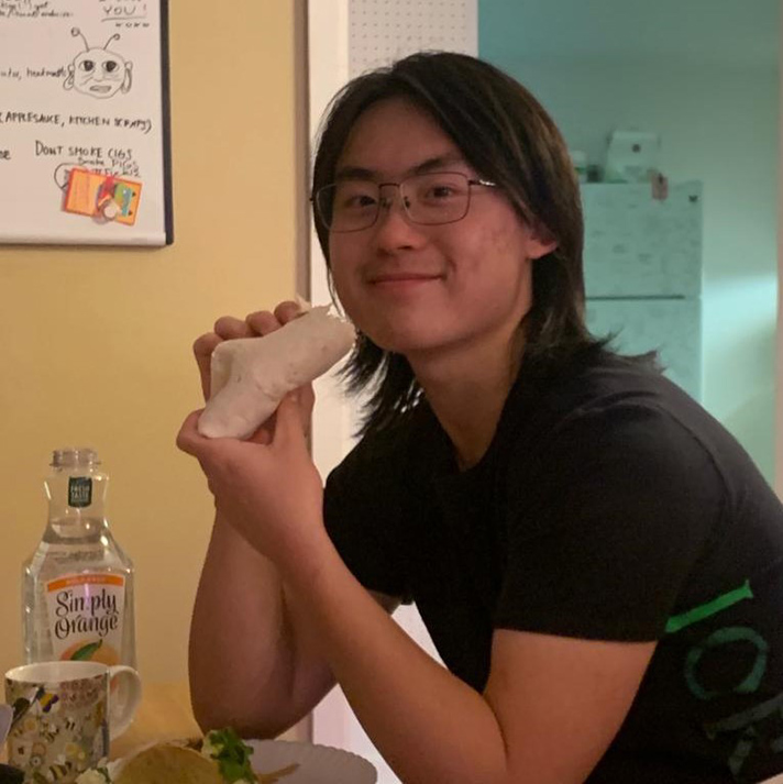 Photo of Edward Cheng in his kitchen eating a sandwich