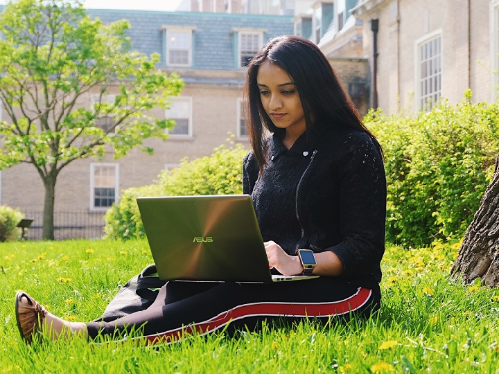 Woman sitting in the grass using a laptop