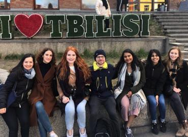 A group of students sit on a curb.