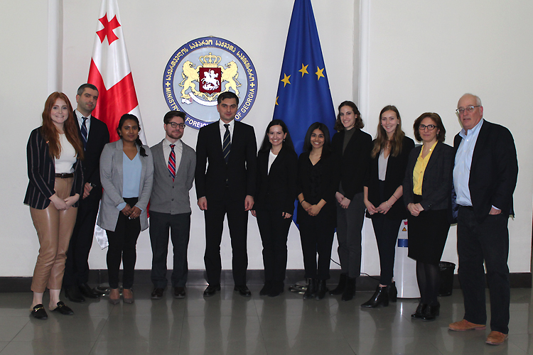 Students, Georgian politicians and Associate Professor Robert Austin stand in front of the Georgian and European Union flags.