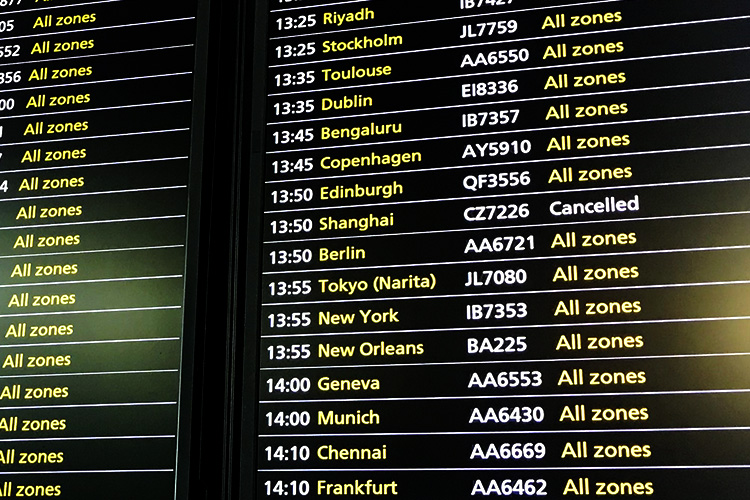 A list of flight schedules in white and yellow text, showing Shanghai flight is cancelled.