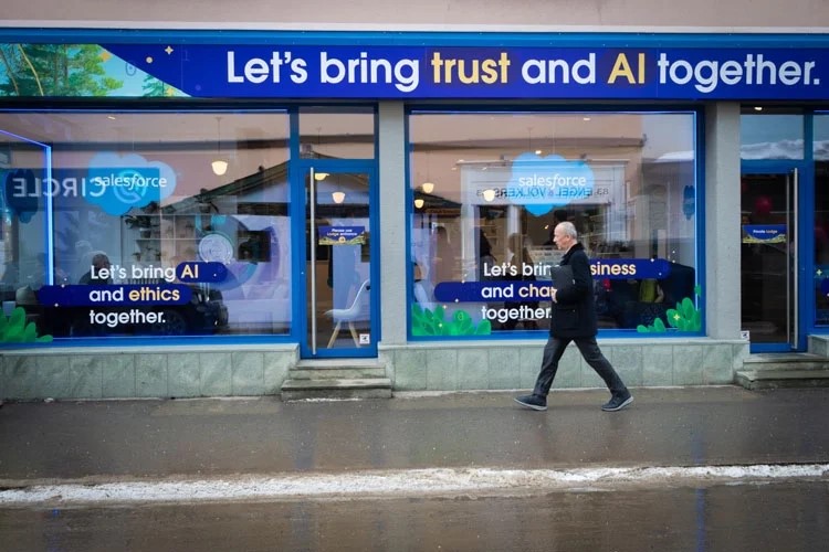 A person walking in front of a building that says, let's bring trust and AI together.