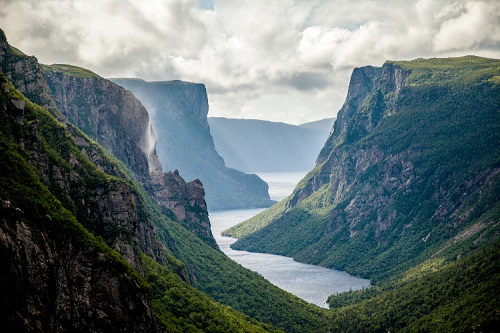 A view of Western Brook Pond Fjord in Newfoundland’s Gros Morne National Park, two cliff's with a stream running in the middle.