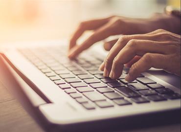 A keyboard and two hands typing.