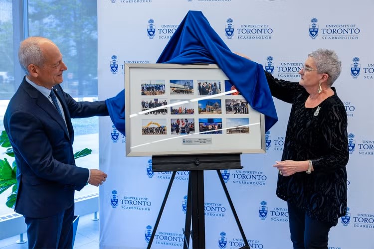 President Meric Gertler is presented with a gift by Linda Johnston.