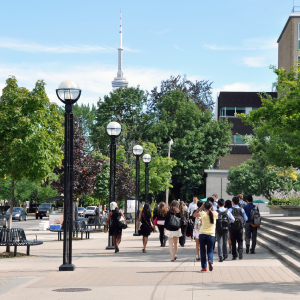 Students walking by Sidney Smith building on a sunny day.