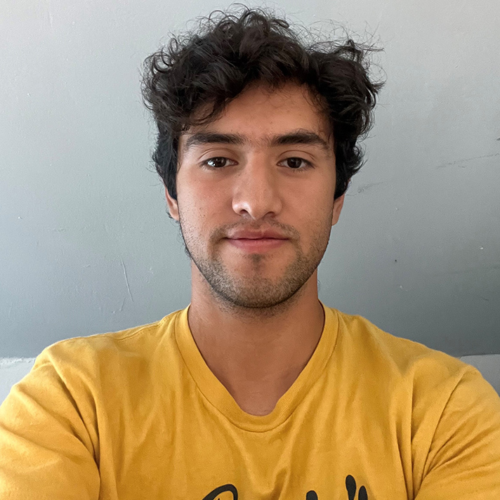 Photo of Jacob Villasana wearing a yellow t-shirt, in front of a white wall