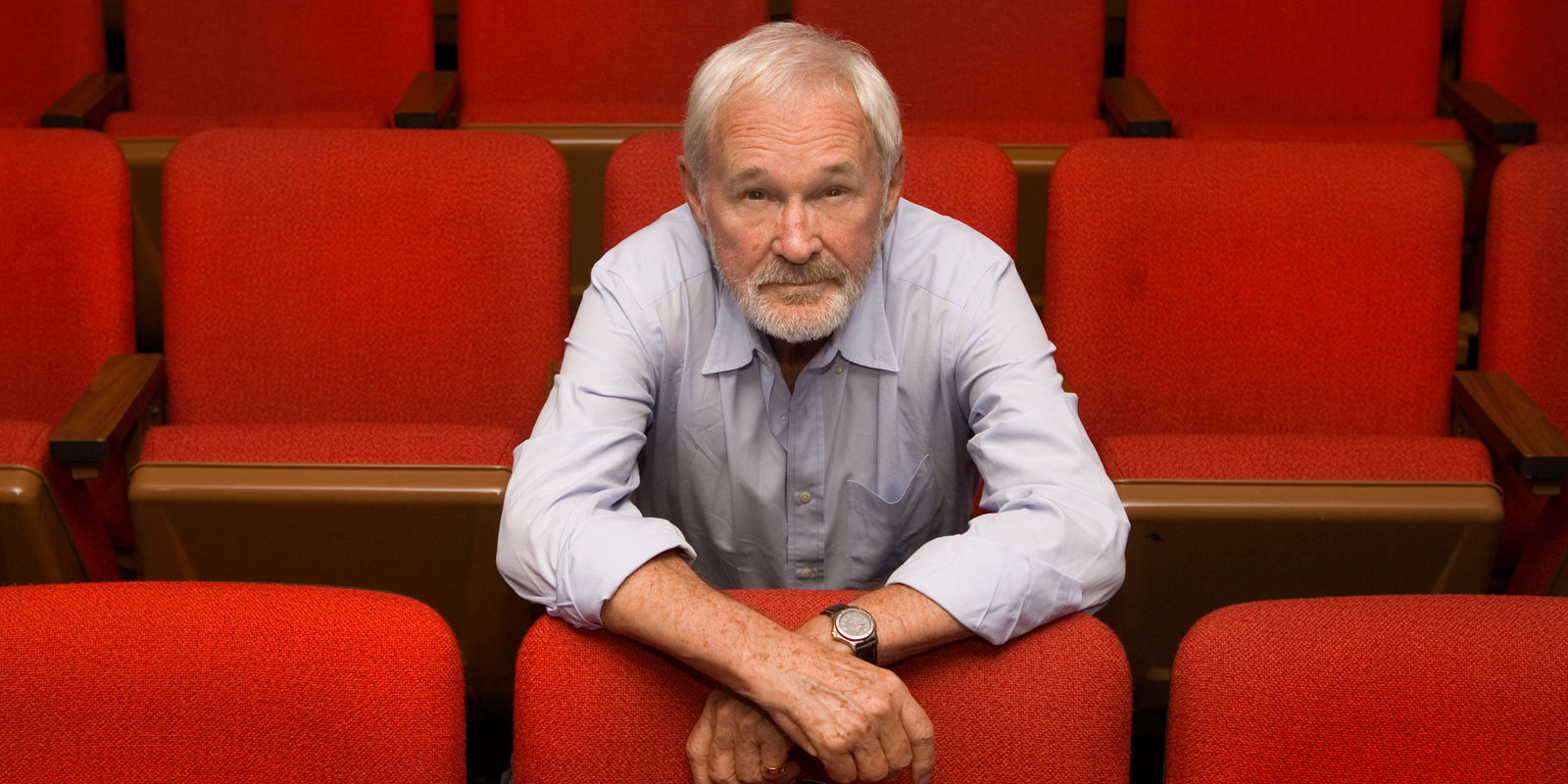 Norman Jewison standing amongst red chairs.