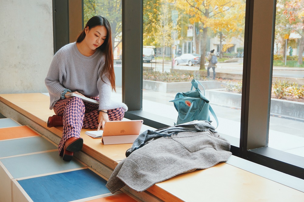 Student working on a laptop by a window ledge