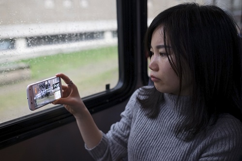 Menglan Li looking out the bus window through her phone