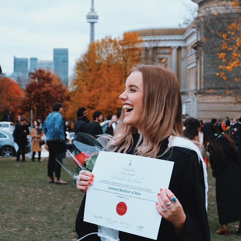 student happily holds up her diploma during convocation