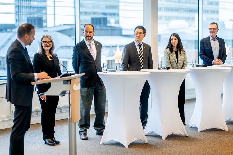 A panel of experts in Stockholm stand in a group around tables.