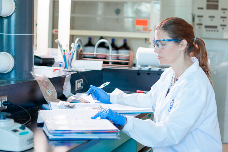 A person with goggles on completing and experiment in a lap.