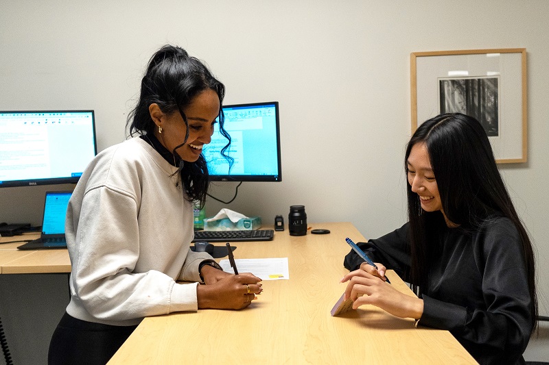 Two students at a standing desk comparing notes