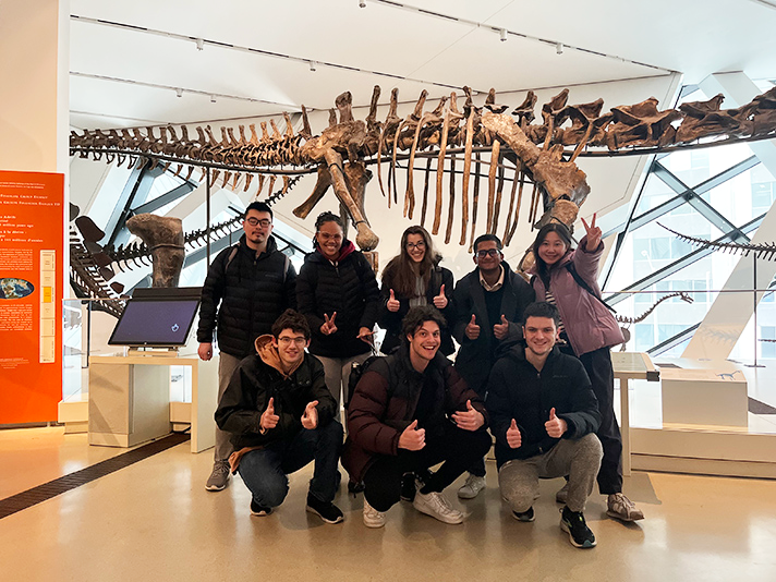 A group of SLC students posing in front of a dinosaur skeleton at ROM