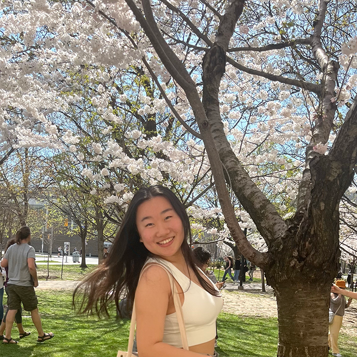 Selina pictured outdoors in front of cherry blossom trees