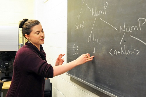 PhD student Shayna Gardiner at a blackboard, writing an equation.