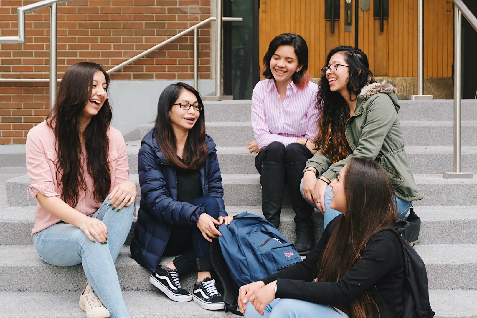 Group of female students sitting on the steps and talking to each other