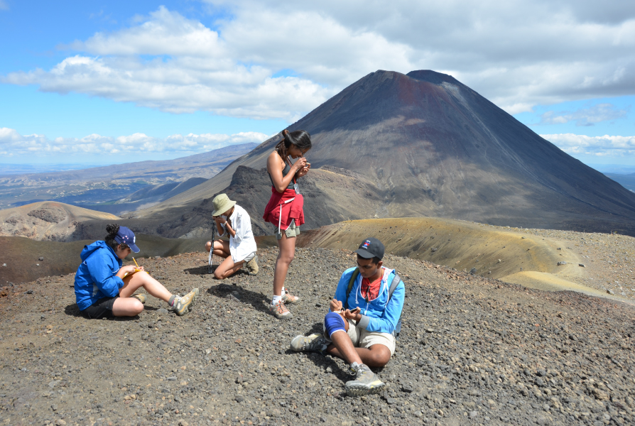 Four students studying objects on a mountain.