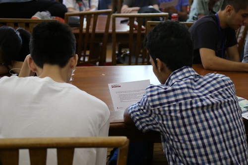Two students, seated facing away from the camera, look at their Words of Wisdom notes