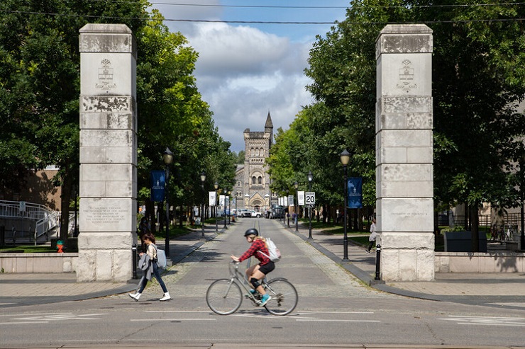 Person riding a bike past the College Street entrance to the St. George campus